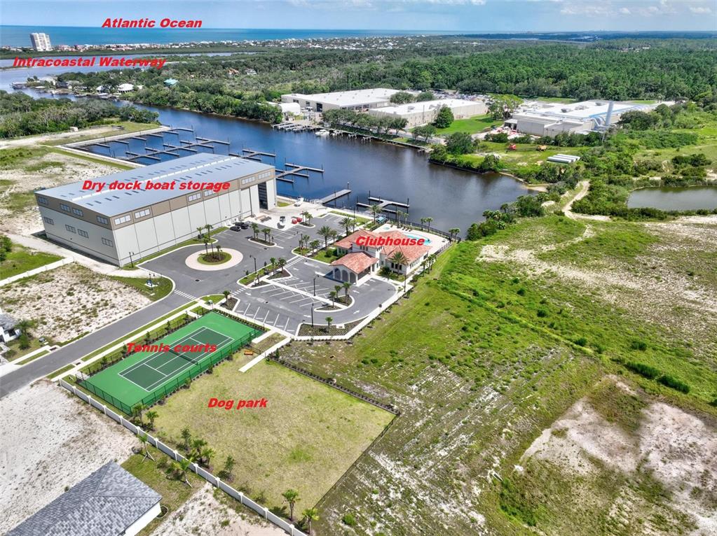 This aerial view shows a marina with a dry dock storage building, clubhouse, and tennis courts — 6 DEL PALMA DRIVE, PALM COAST, FL