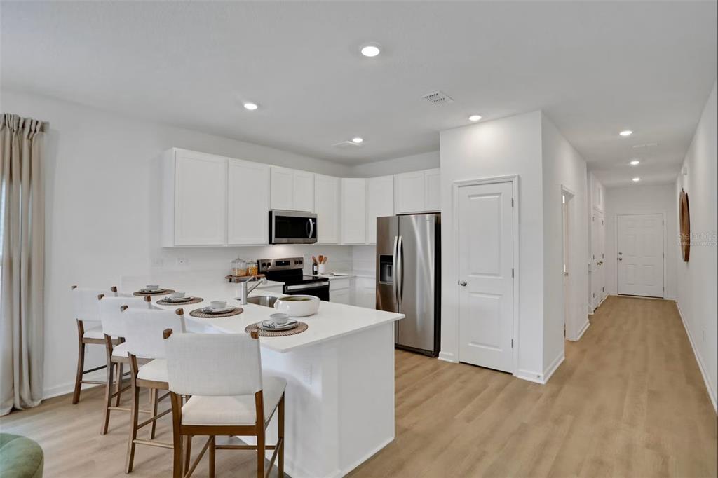 A modern kitchen features white cabinetry, stainless steel appliances, and a breakfast bar with seating — 7634 COMMANDER LANE, JACKSONVILLE, FL