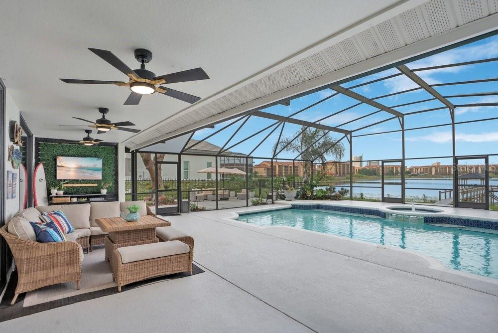 A covered patio features wicker furniture, ceiling fans, and a screened-in pool overlooking a lake — 10094 BRANDON CIRCLE, ORLANDO, FL