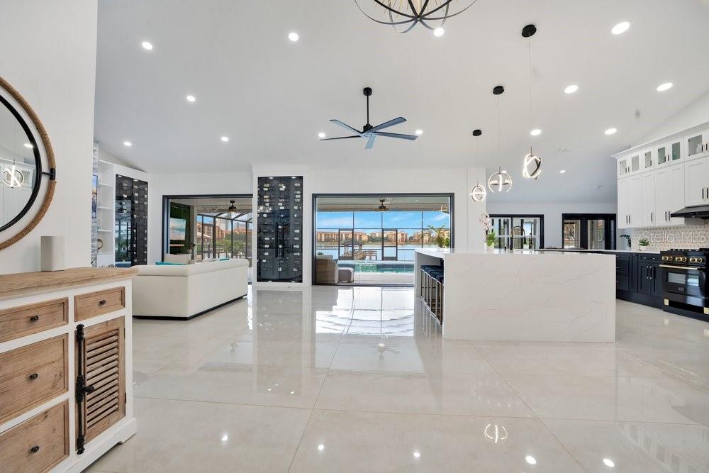 A spacious open-concept kitchen and living area with white cabinetry, a large island, and water views — 10094 BRANDON CIRCLE, ORLANDO, FL