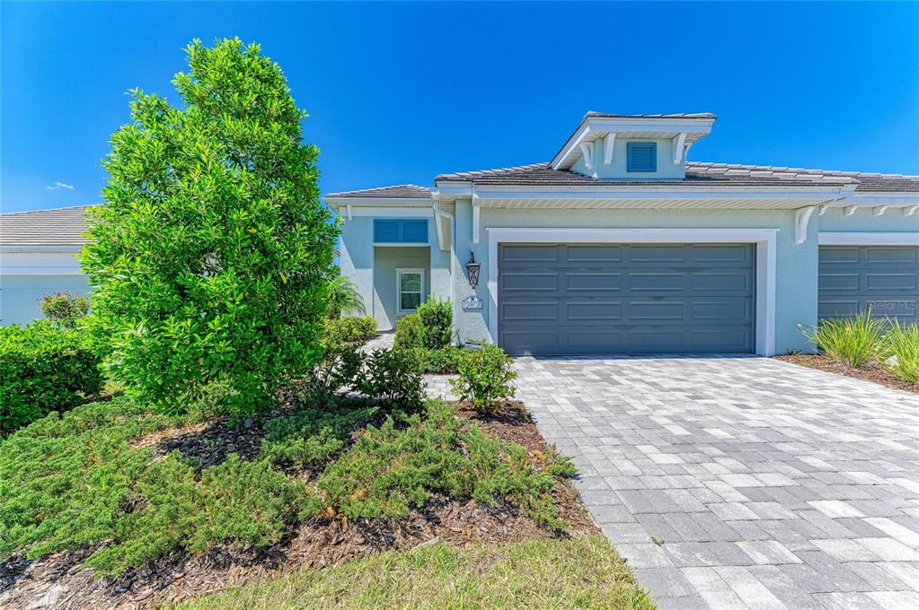 A light blue single-story house features a gray garage door and a paved driveway — 12807 SEASONG TERRACE, BRADENTON, FL