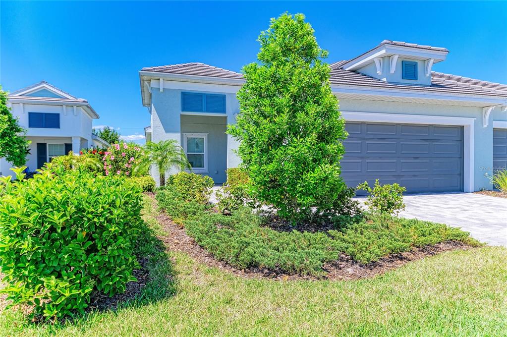 A single-story house with a gray garage, light blue stucco, and landscaped front yard — 12807 SEASONG TERRACE, BRADENTON, FL