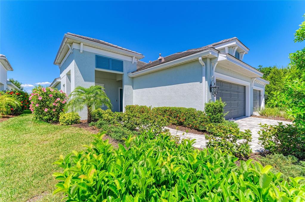A light blue single-story house with a two-car garage and landscaped front yard — 12807 SEASONG TERRACE, BRADENTON, FL