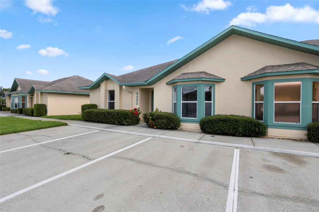A single-story building with a beige stucco exterior, teal trim, and a concrete parking area — 3200 VILLA WAY CIRCLE, ST CLOUD, FL