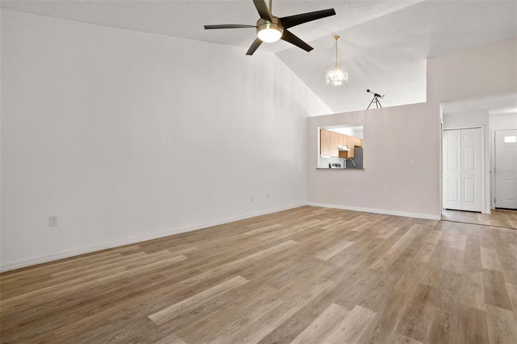 An empty living room features vaulted ceilings, a ceiling fan, and light wood-look flooring — 3200 VILLA WAY CIRCLE, ST CLOUD, FL