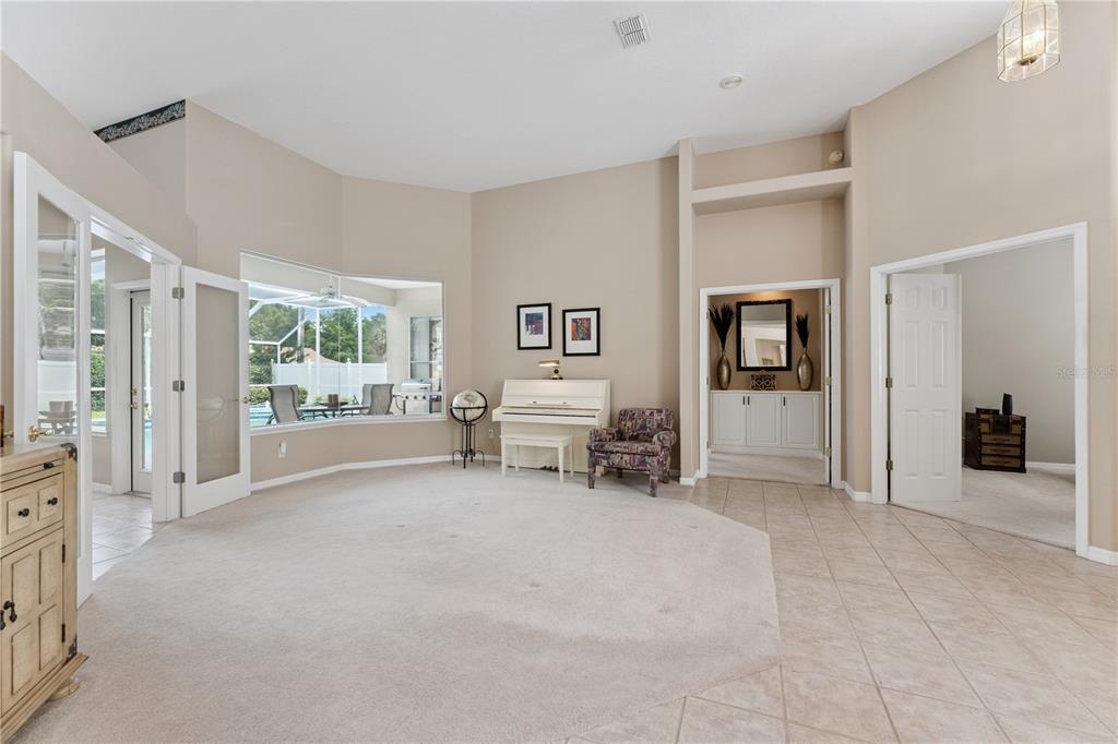 A spacious living room features beige carpet, tile flooring, a white piano, and a bay window — 3823 WINDING LAKE CIRCLE, ORLANDO, FL