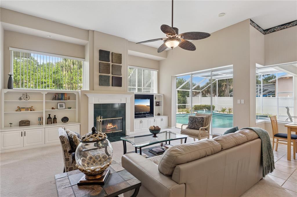 A living room features a fireplace, built-in shelving, a ceiling fan, and sliding glass doors — 3823 WINDING LAKE CIRCLE, ORLANDO, FL