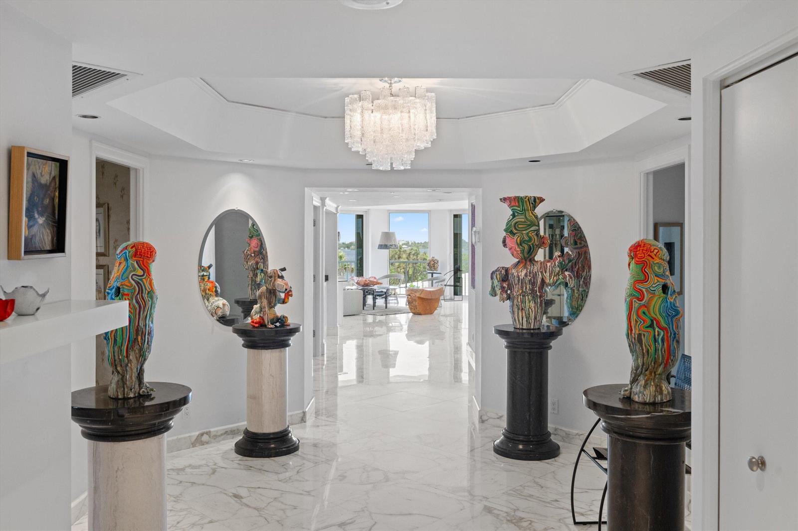 A bright foyer features marble floors, a crystal chandelier, and four colorful sculptures on pedestals — 3170 S Ocean Boulevard # 305s, Palm Beach FL 33480, PALM BEACH, FL