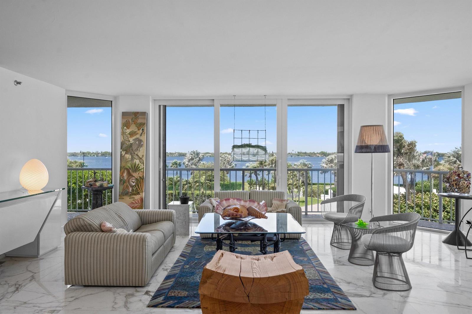 A living room features marble floors, a striped sofa, and floor-to-ceiling windows overlooking the water — 3170 S Ocean Boulevard # 305s, Palm Beach FL 33480, PALM BEACH, FL