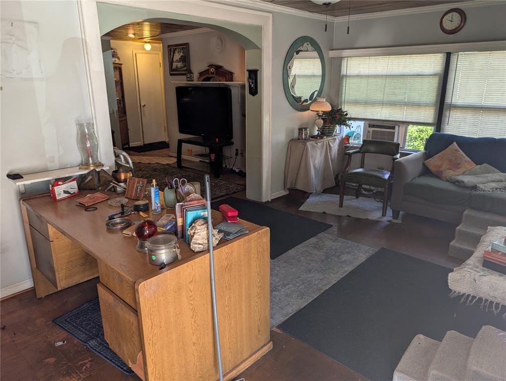 A living room features a wooden desk in the foreground and a sofa by a window — 4079 LAKE MARIANNA DRIVE, WINTER HAVEN, FL