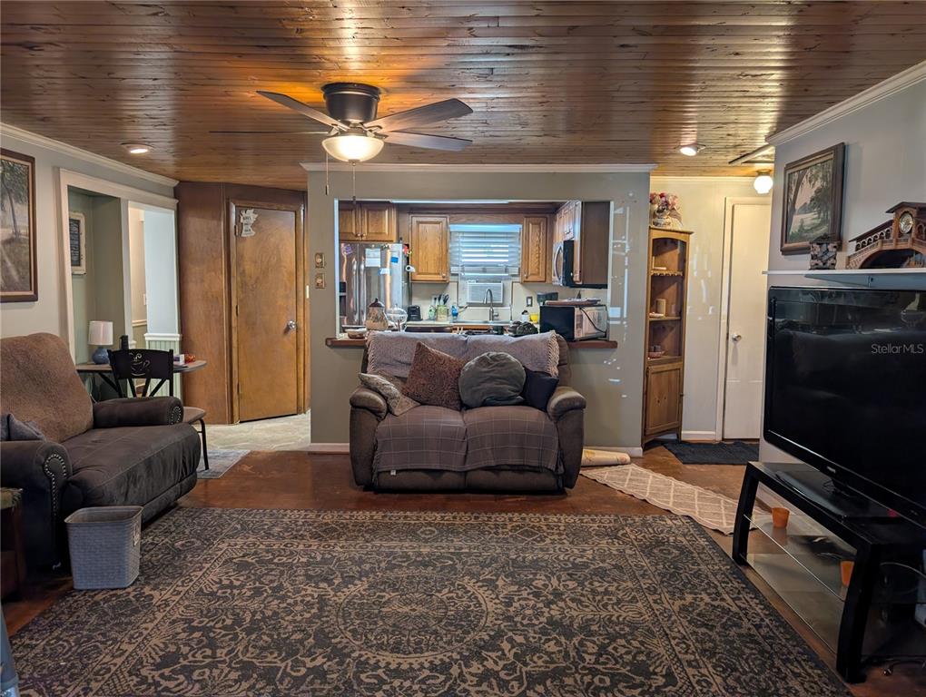 A living room features a wood-paneled ceiling, a ceiling fan, and an open kitchen pass-through — 4079 LAKE MARIANNA DRIVE, WINTER HAVEN, FL