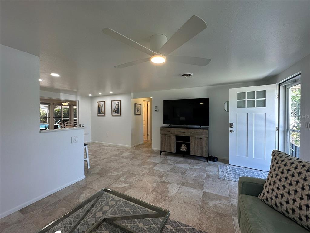 A living room with tile floors, a ceiling fan, a television console, and an entryway — 1575 LORALIN DRIVE, ENGLEWOOD, FL