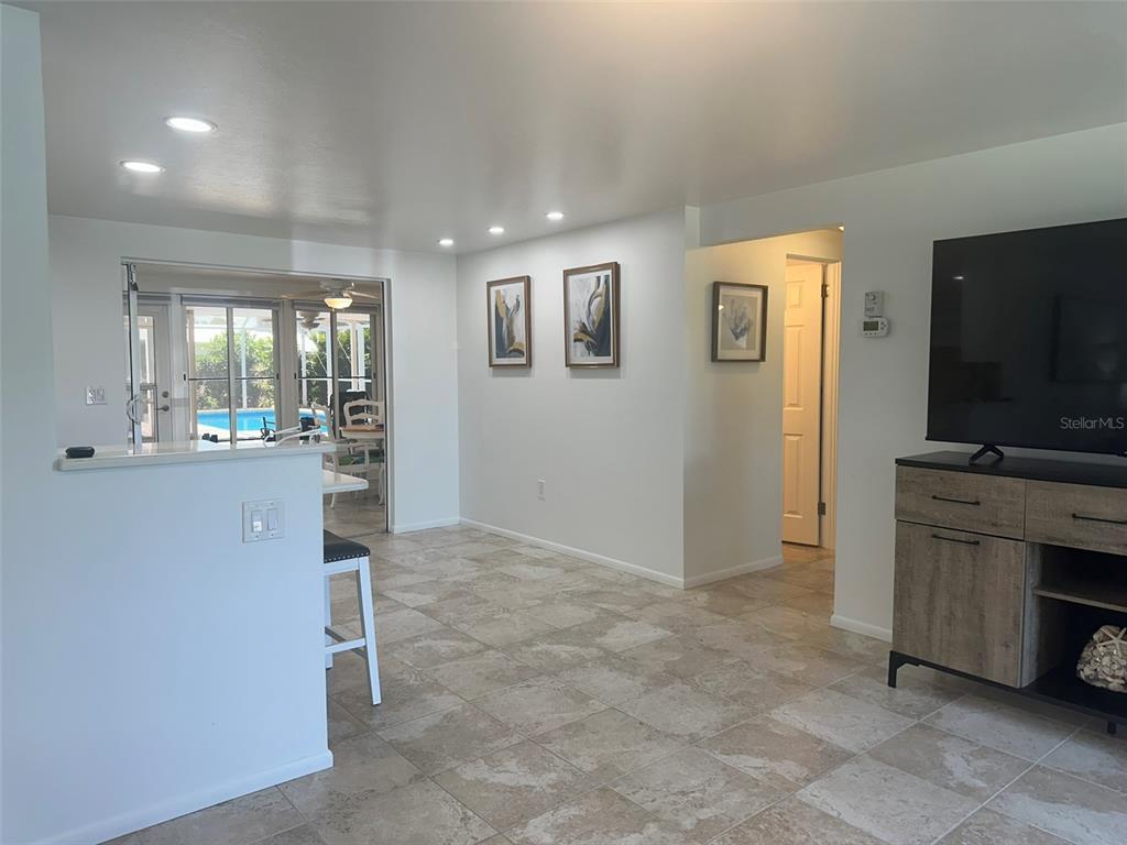 A bright living area features tile flooring, recessed lighting, wall art, and a view of a pool — 1575 LORALIN DRIVE, ENGLEWOOD, FL