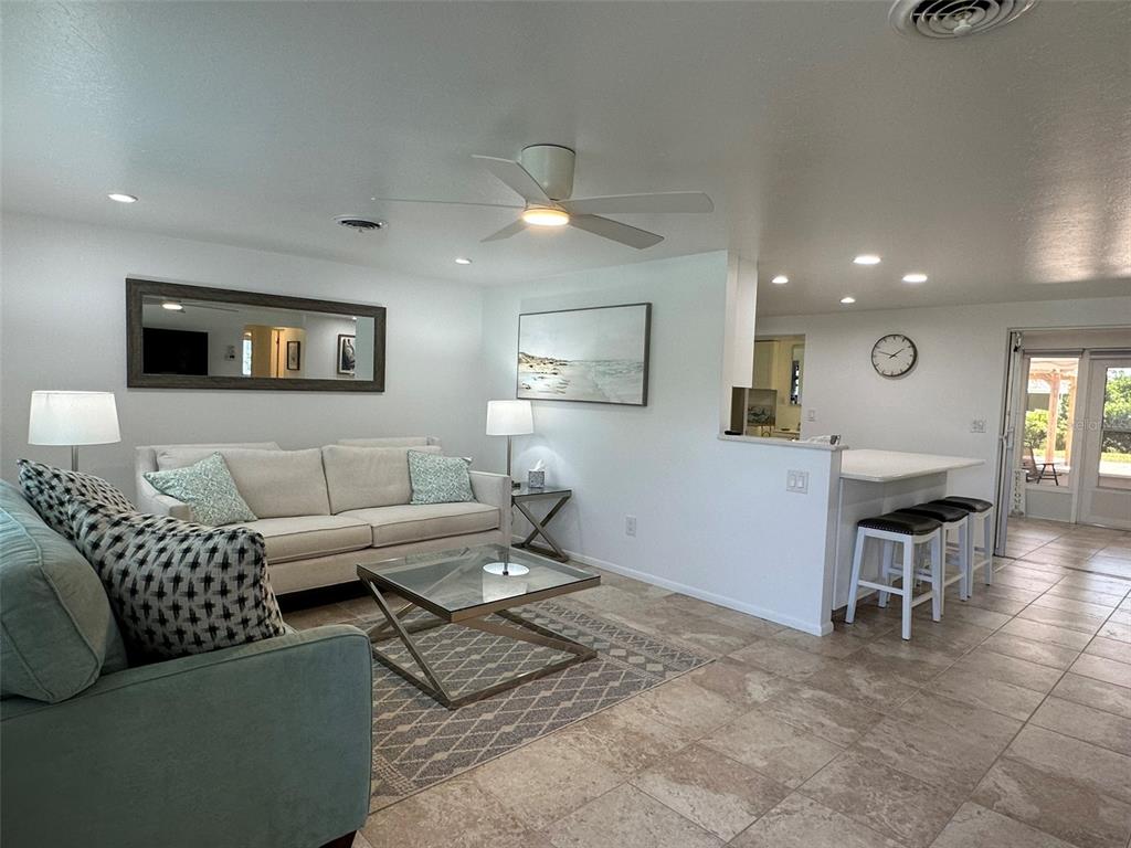 A living room with a sofa, glass coffee table, and an adjacent kitchen breakfast bar — 1575 LORALIN DRIVE, ENGLEWOOD, FL