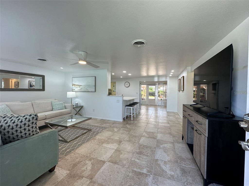A living room with tile floors, a kitchen breakfast bar, and a large television console — 1575 LORALIN DRIVE, ENGLEWOOD, FL
