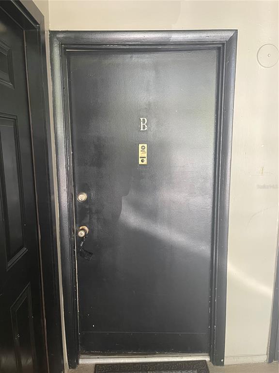 A black front door with a letter B, a peephole, and two door locks — 134 SPRINGWOOD CIRCLE UNIT B, LONGWOOD, FL