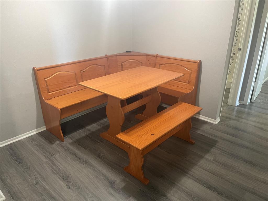 A wooden corner breakfast nook set sits on gray wood-look flooring in a room — 134 SPRINGWOOD CIRCLE UNIT B, LONGWOOD, FL
