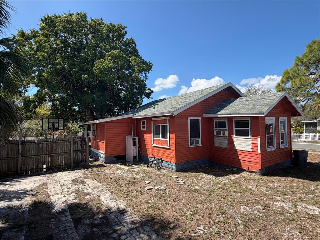 A small, orange-sided house with a shingled roof and a fenced yard — 2500 OAKDALE STREET S, ST PETERSBURG, FL
