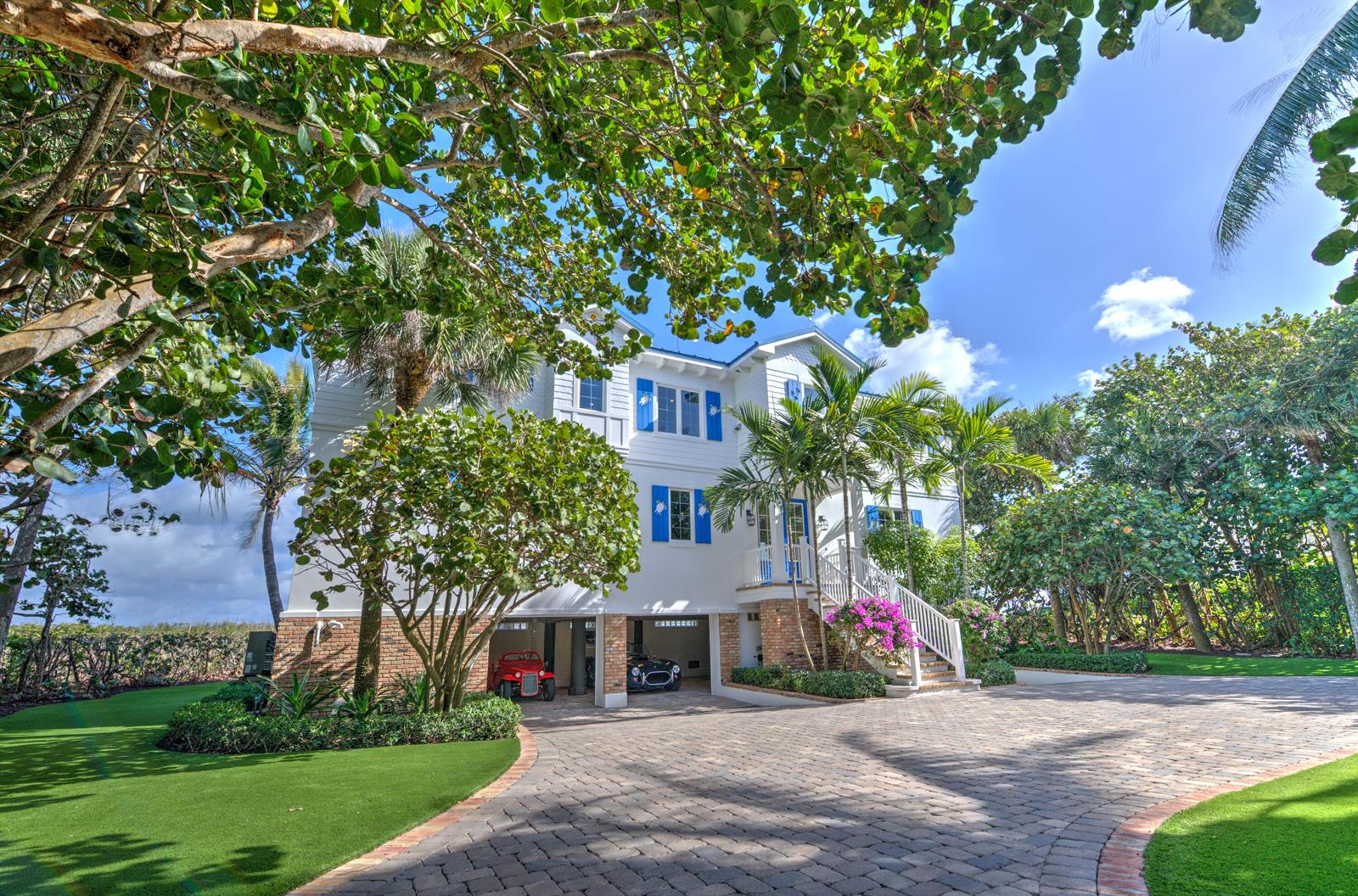 A white three-story house with blue shutters and a paved driveway featuring two parked cars — 113 N Beach Road, Jupiter Island FL 33455, JUPITER ISLAND, FL