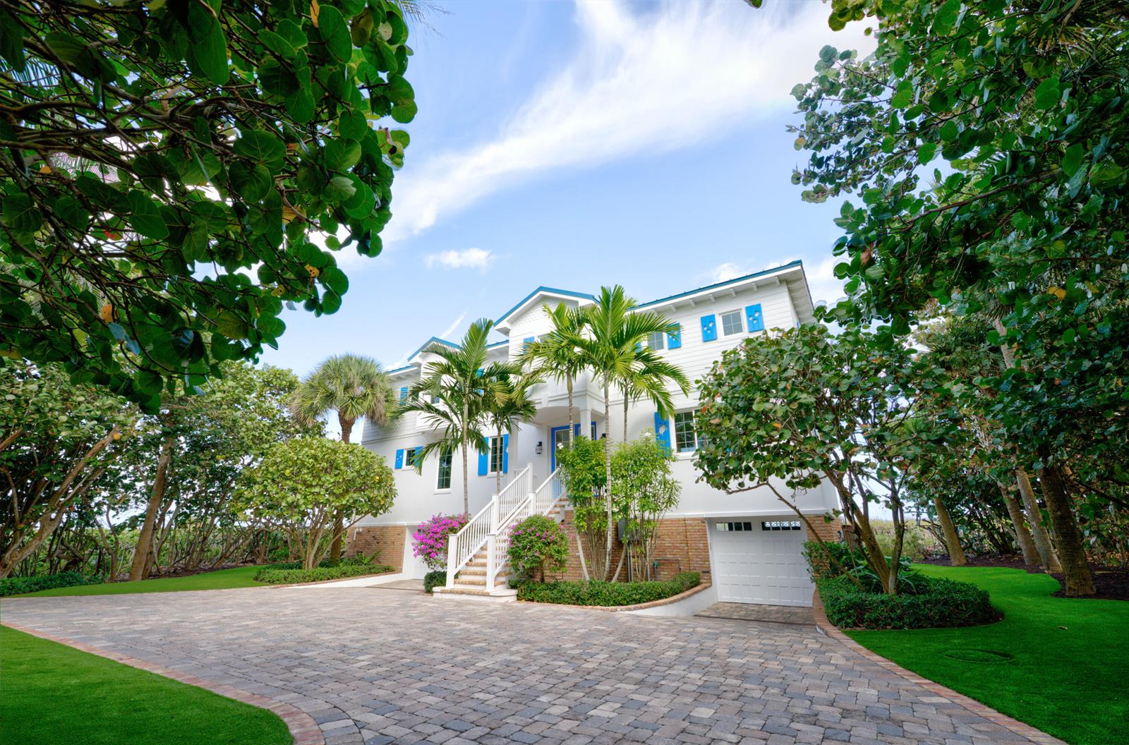 A white three-story house with blue shutters and a paved driveway surrounded by lush trees — 113 N Beach Road, Jupiter Island FL 33455, JUPITER ISLAND, FL