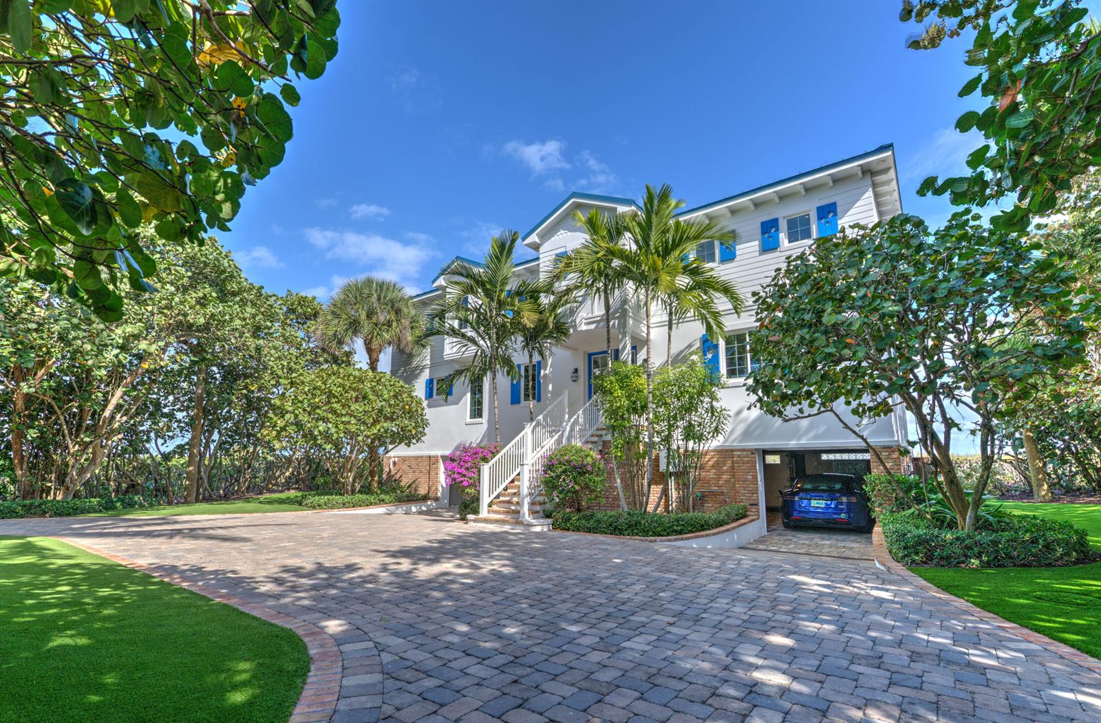 A three-story white house with blue shutters and a paved driveway sits among lush trees — 113 N Beach Road, Jupiter Island FL 33455, JUPITER ISLAND, FL