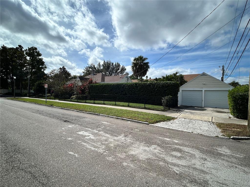 A street view of a house with a large hedge, black fence, and detached garage — 701 29TH AVENUE N, ST PETERSBURG, FL