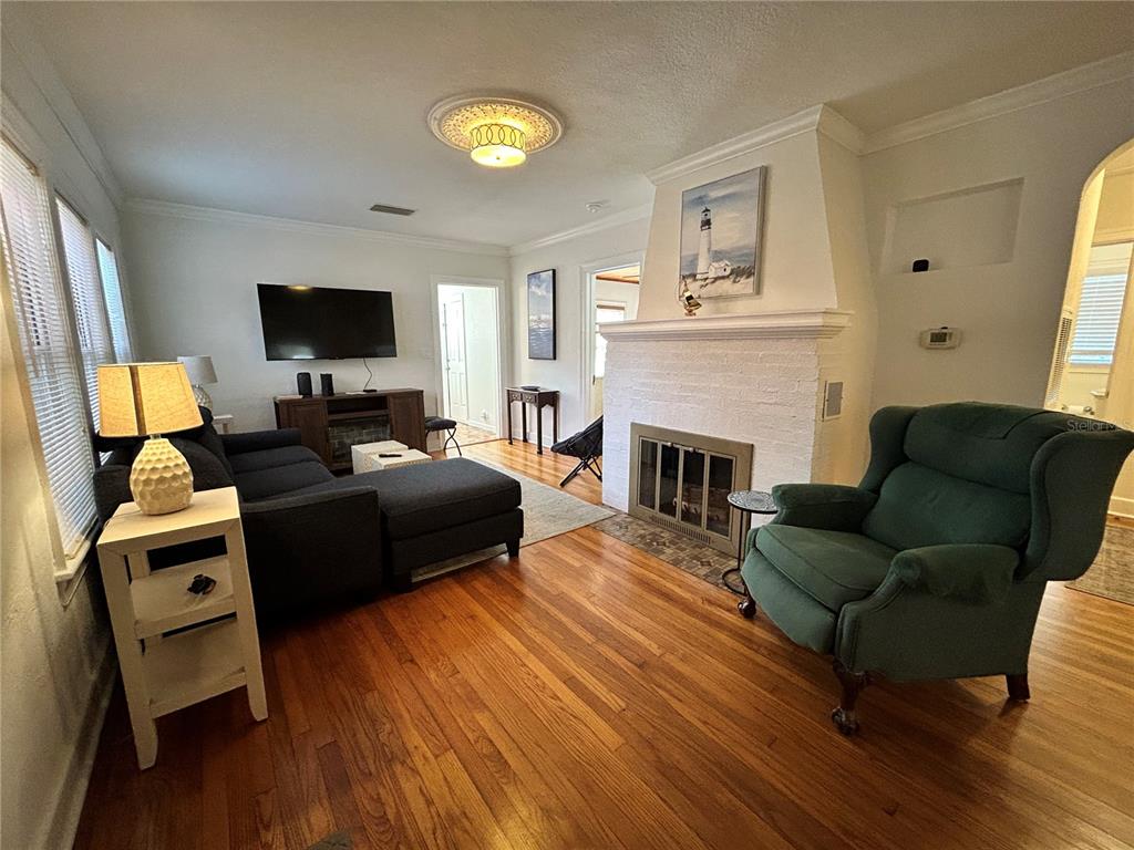 A living room features hardwood floors, a white brick fireplace, and a dark sectional sofa — 701 29TH AVENUE N, ST PETERSBURG, FL