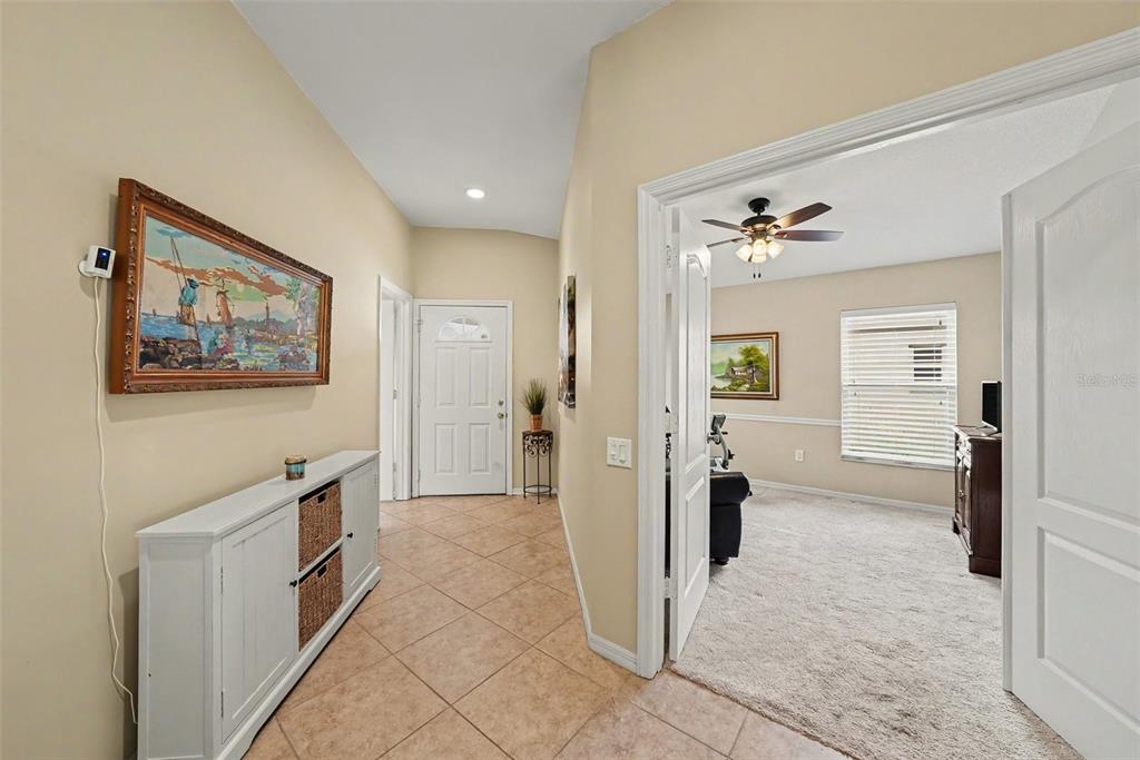 A tiled entryway leads to a white front door and an adjacent carpeted room — 26351 WHIRLAWAY TERRACE, WESLEY CHAPEL, FL
