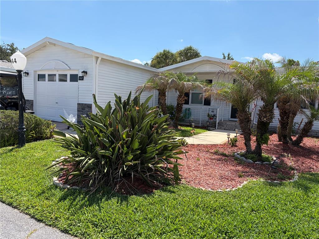 A white single-story house with a garage, palm trees, and a landscaped front yard — 144 VICTORIA DRIVE, HAINES CITY, FL