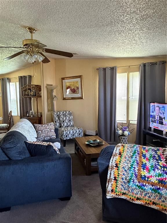 A living room features a ceiling fan, dark sofas, a coffee table, and window curtains — 144 VICTORIA DRIVE, HAINES CITY, FL