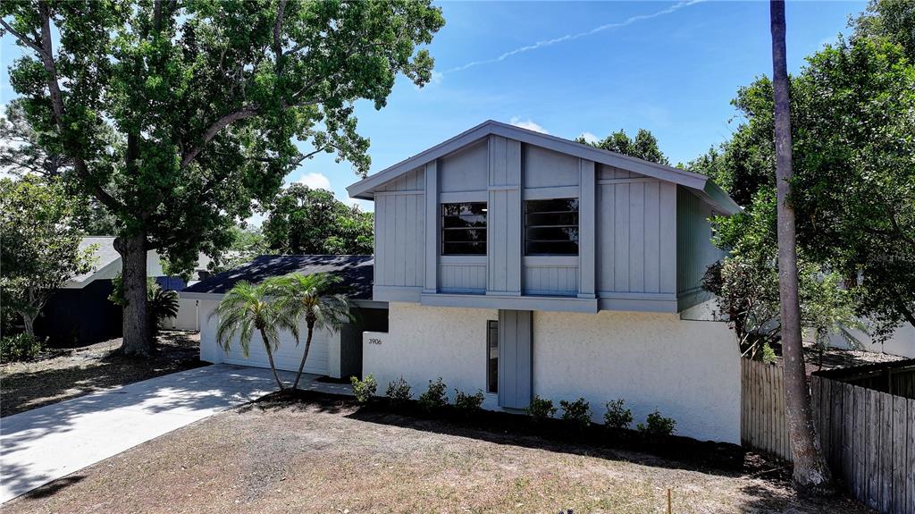 A two-story house with a white stucco lower level and gray vertical siding above — 3906 BLOOMING HILL LANE, PALM HARBOR, FL