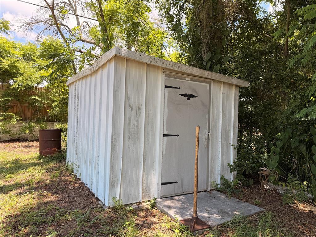 A weathered white metal storage shed stands in a grassy yard near trees — 66 S WASHINGTON STREET, BEVERLY HILLS, FL