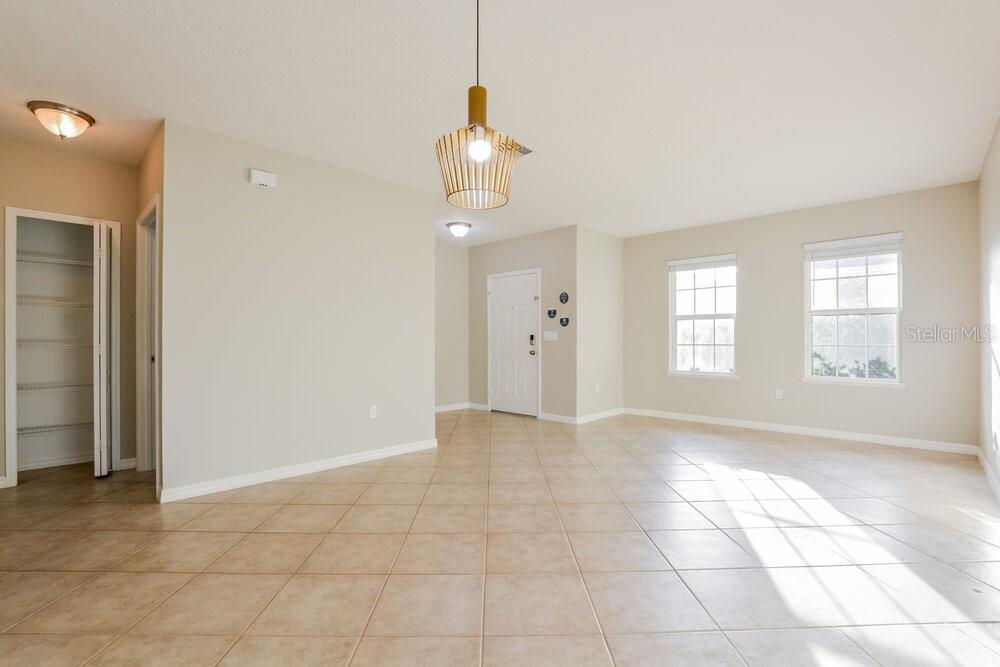 An empty room with beige walls, tile flooring, a pendant light, and a closet — 3627 RYEGRASS STREET, CLERMONT, FL