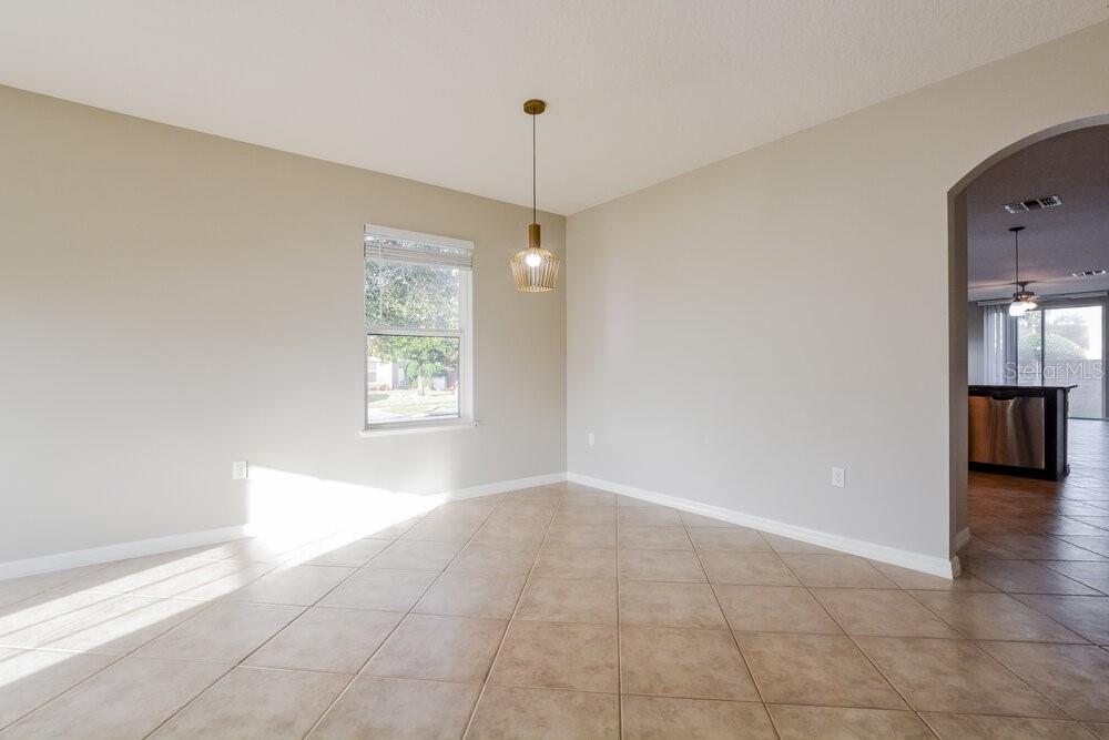A dining area with beige walls, tile flooring, a single pendant light, and a window — 3627 RYEGRASS STREET, CLERMONT, FL