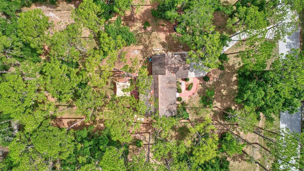 An aerial view shows a house nestled among many trees with a paved driveway — 9607 OAK RUN DRIVE, BRADENTON, FL