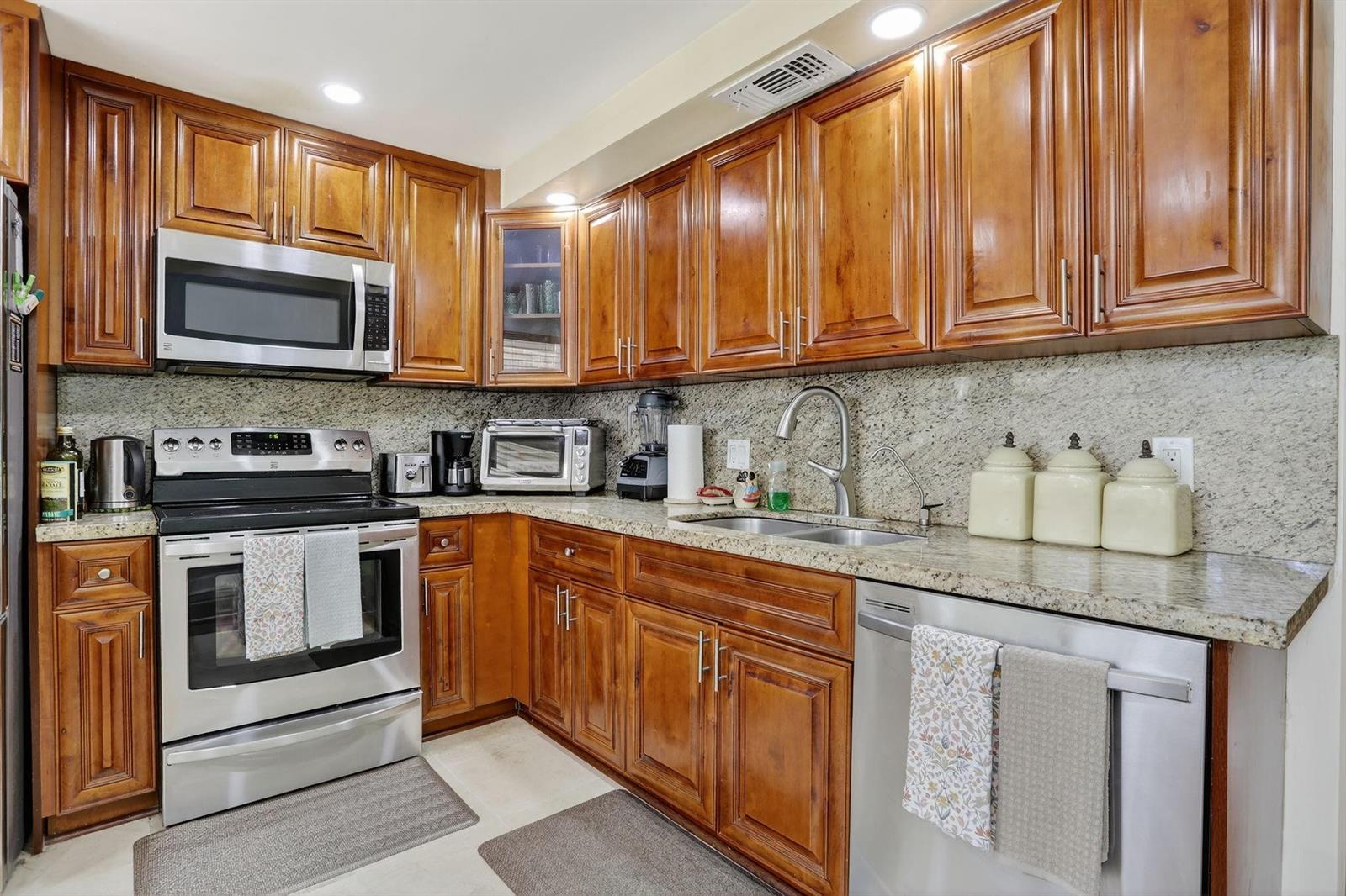 A kitchen features wood cabinets, granite countertops, stainless steel appliances, and a double-basin sink — 2403 Antigua Circle # B2, Coconut Creek FL 33066, COCONUT CREEK, FL