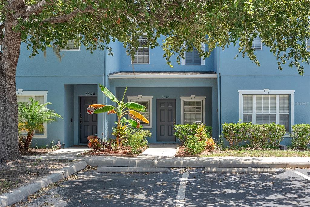 The exterior of a two-story blue townhouse features two front doors and a parking lot — 6737 LAKE ROCHESTER LANE, GIBSONTON, FL