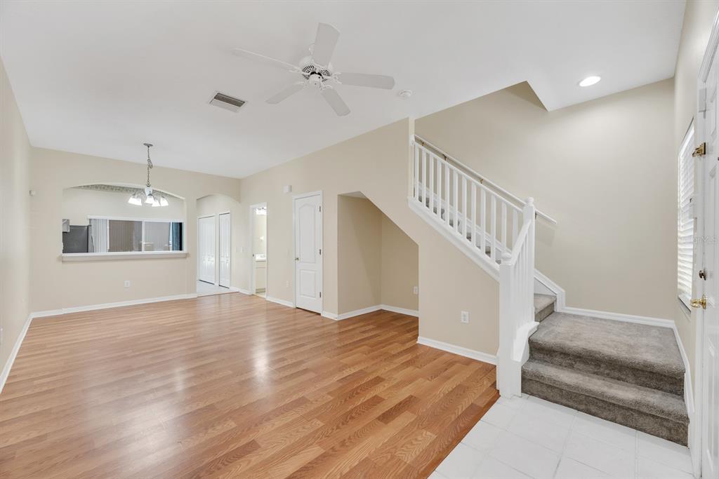 An interior view of a living room with hardwood floors, a staircase, and a kitchen pass-through — 6737 LAKE ROCHESTER LANE, GIBSONTON, FL