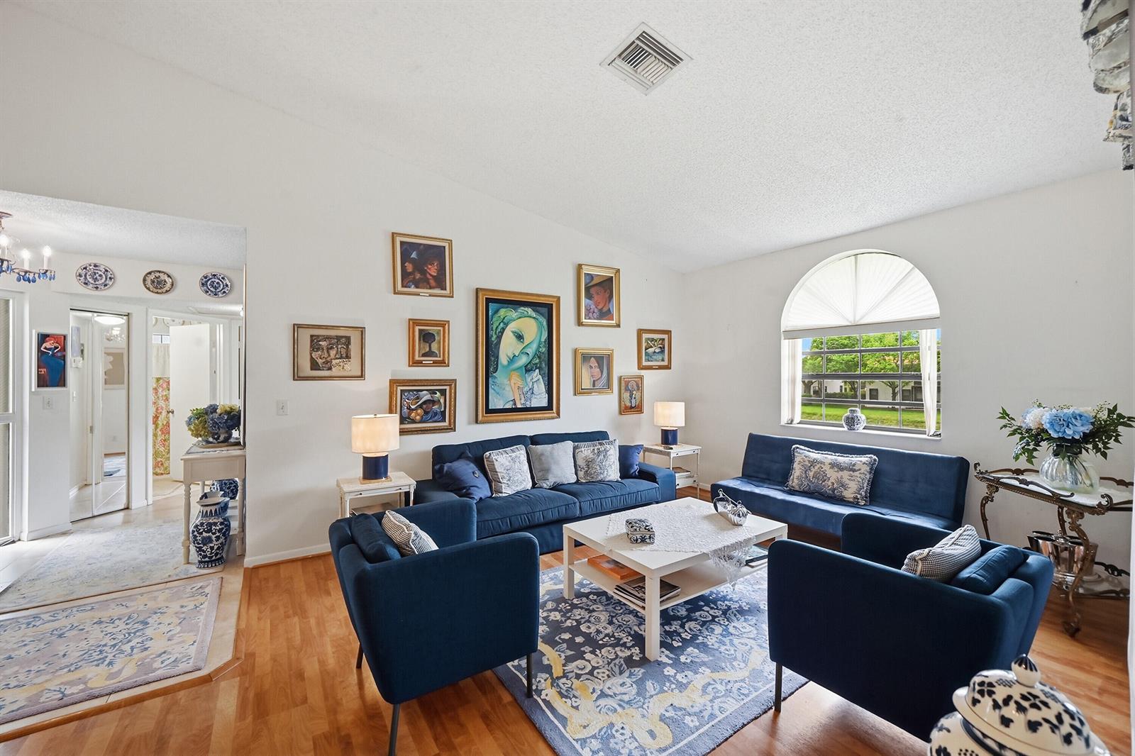 A living room features blue furniture, a white coffee table, and a gallery wall of art — 5442 Firenze Drive # F, Boynton Beach FL 33437, BOYNTON BEACH, FL