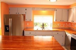 A kitchen features light-colored cabinets, a stainless steel refrigerator, and a wooden countertop island — 3601 62ND STREET W, BRADENTON, FL