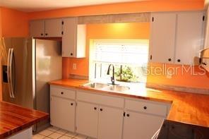A kitchen features light gray cabinets, a stainless steel refrigerator, and wood countertops — 3601 62ND STREET W, BRADENTON, FL