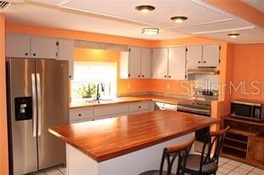 A kitchen with white cabinets, stainless steel appliances, and a large wooden island countertop — 3601 62ND STREET W, BRADENTON, FL
