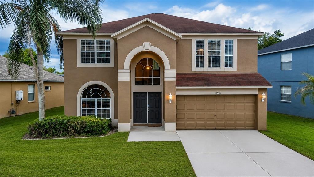 A two-story tan house with a brown roof, arched entryway, and a two-car garage — 10526 BENEVA DRIVE, TAMPA, FL