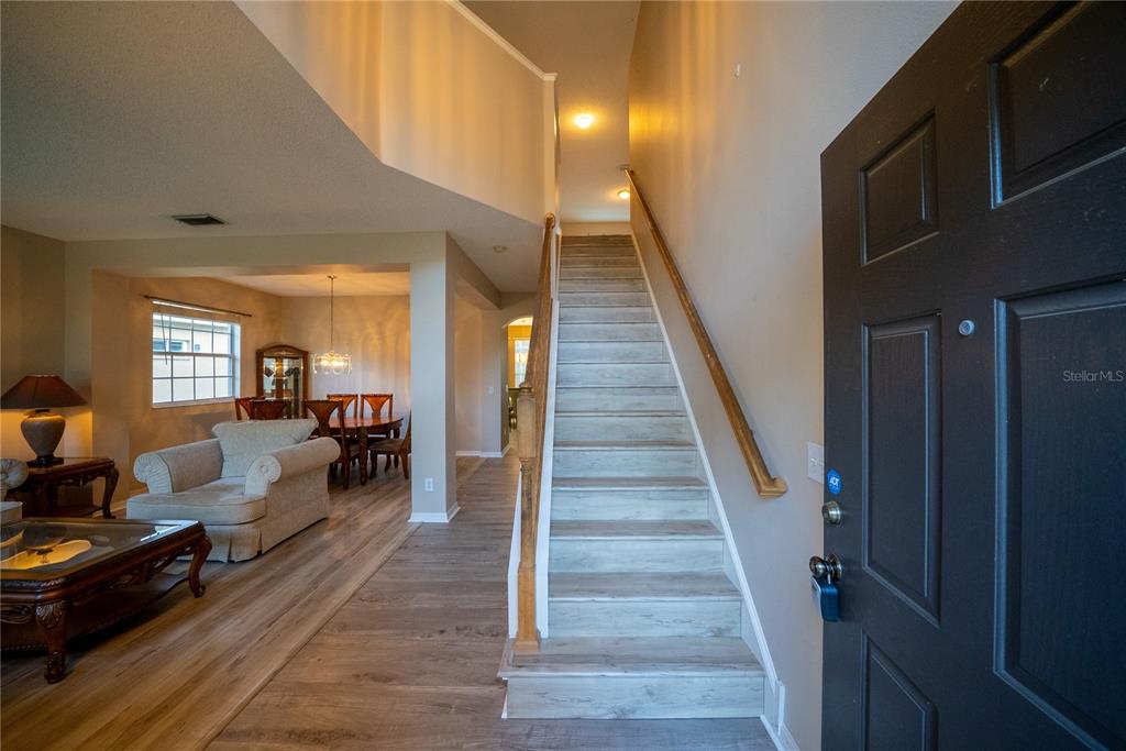 An entryway features light wood-look flooring, a staircase with a wooden railing, and an adjacent dining area — 10526 BENEVA DRIVE, TAMPA, FL