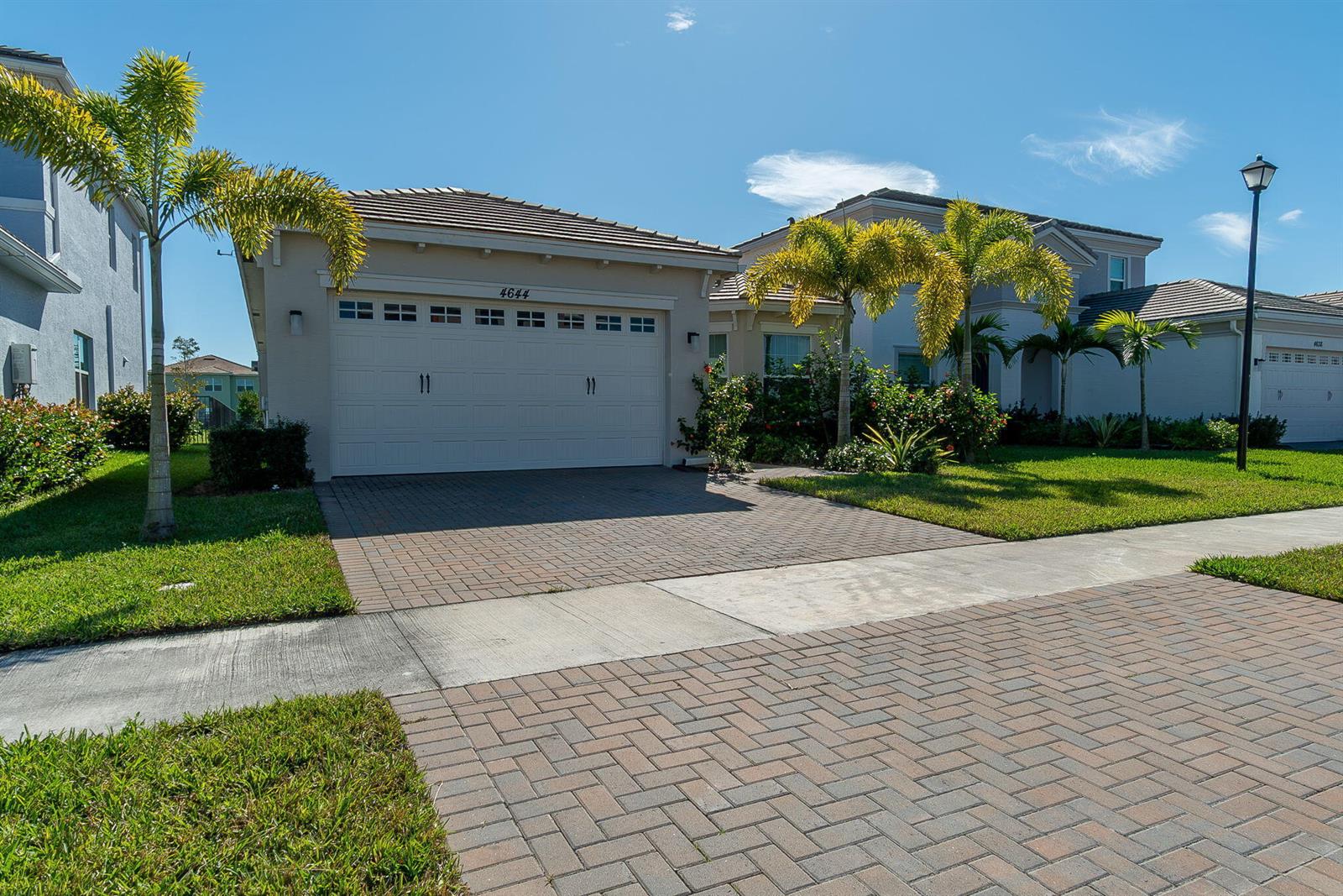 A single-story house with a white garage door, brick paver driveway, and palm trees — 4644 Citron Way, Westlake FL 33470, WESTLAKE, FL