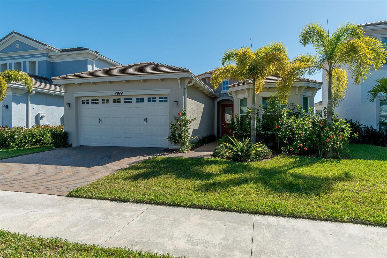 A single-story suburban house with a tan stucco exterior, a two-car garage, and palm trees — 4644 Citron Way, Westlake FL 33470, WESTLAKE, FL