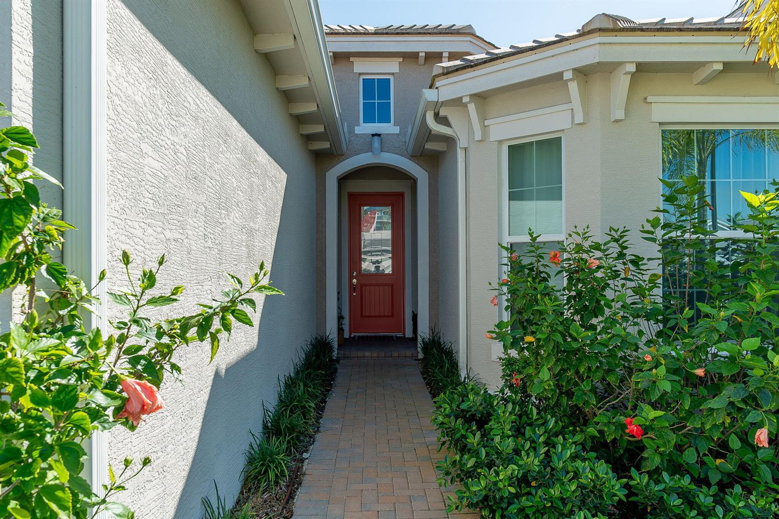 A brick walkway leads to a red front door framed by a stucco exterior — 4644 Citron Way, Westlake FL 33470, WESTLAKE, FL