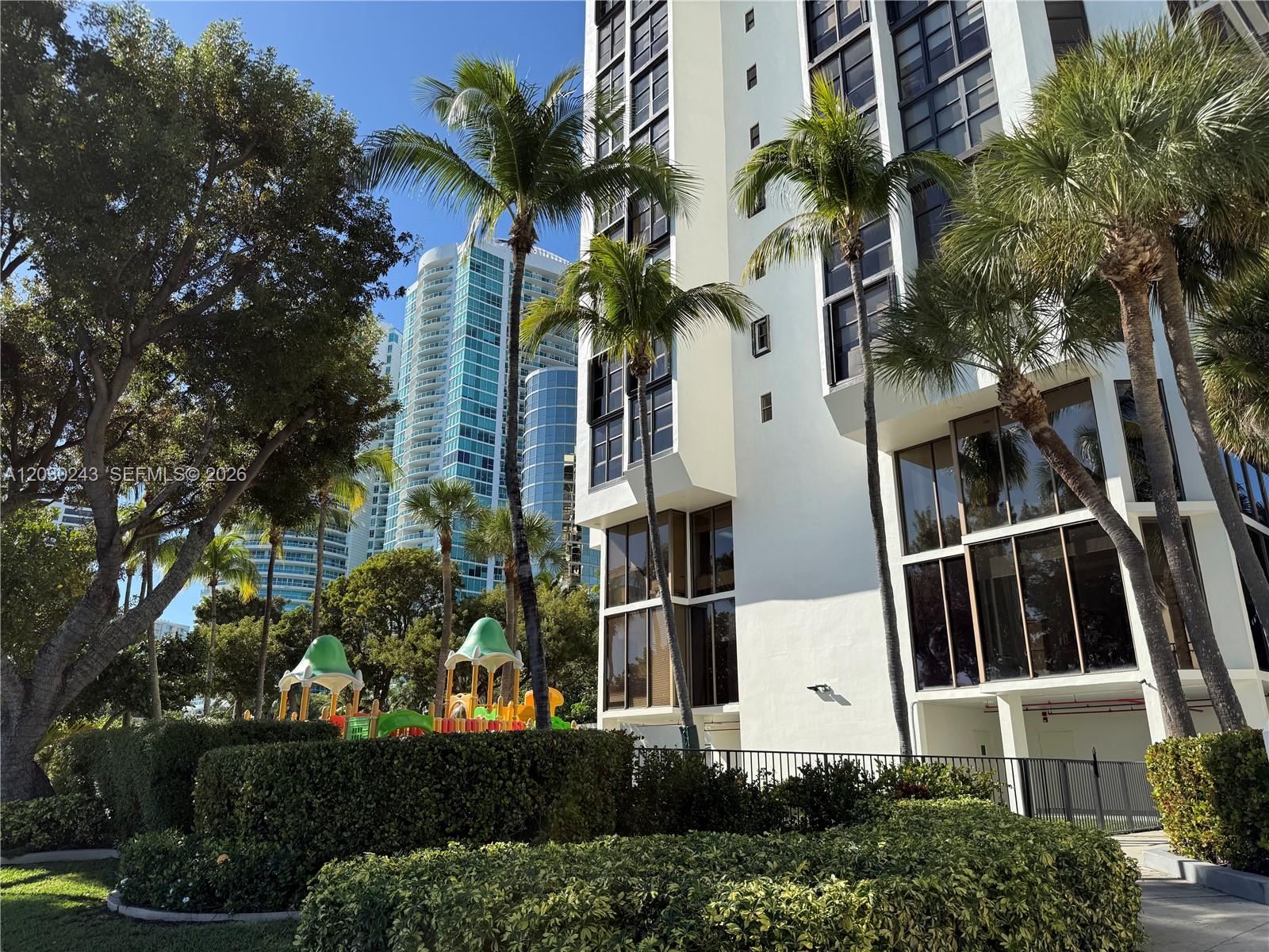 A white high-rise building stands next to a playground and palm trees — 1925 Brickell Ave # 1403, Miami FL 33129, MIAMI, FL