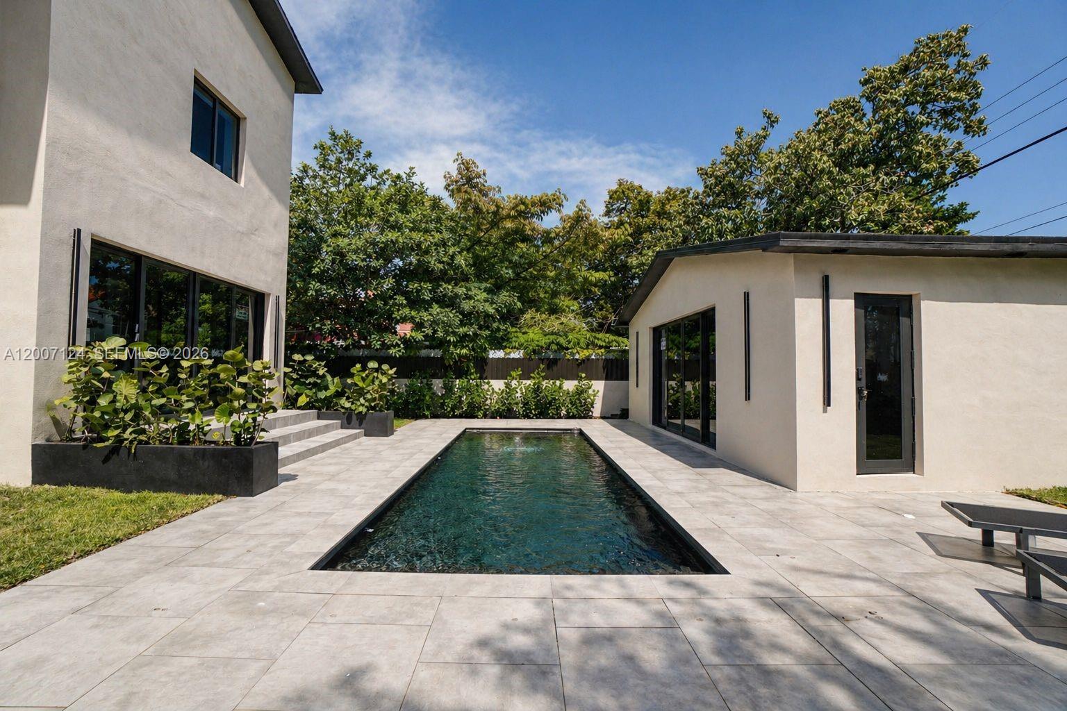 A rectangular swimming pool sits between a two-story house and a detached structure — 1820 SW 10th St, Miami FL 33135, MIAMI, FL