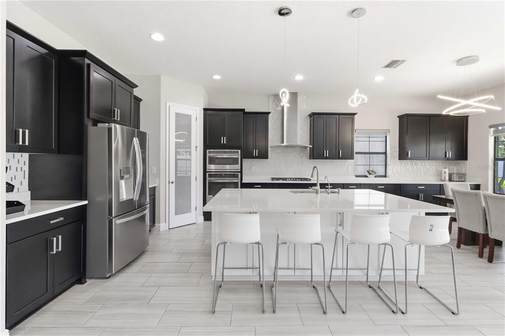 A modern kitchen features dark cabinetry, a white island with bar stools, and stainless appliances — 805 VISCOUNT STREET, BRANDON, FL